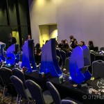 A group of people sitting at tables with blue chairs