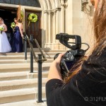 A woman taking a picture of a bride and groom
