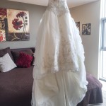 A wedding dress hanging on a hanger in a room