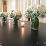 A group of vases filled with white flowers on a table