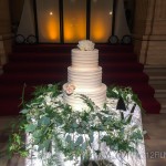 A wedding cake with flowers and greenery on a table