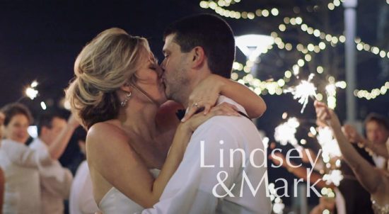 A bride and groom kissing with sparklers in the background