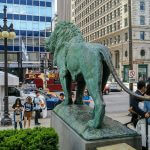 A statue of a lion in the middle of a Chicago city Art Institute