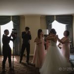 A group of people taking pictures of a bride and groom