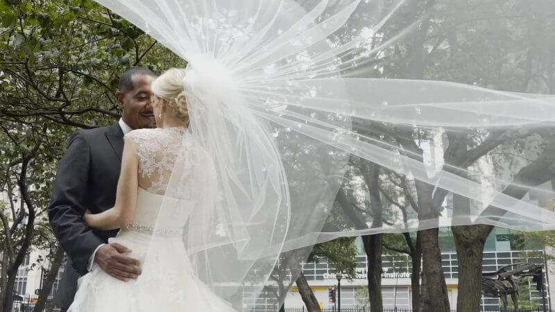 A bride and groom kissing under a veil
