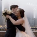 A bride and groom embracing in front of a city skyline