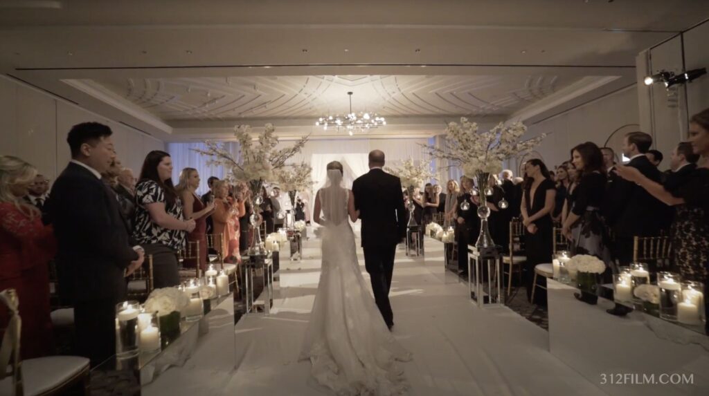 The bride walks down the aisle at the Juliette Ballroom at the LondonHouse Chicago during her wedding.