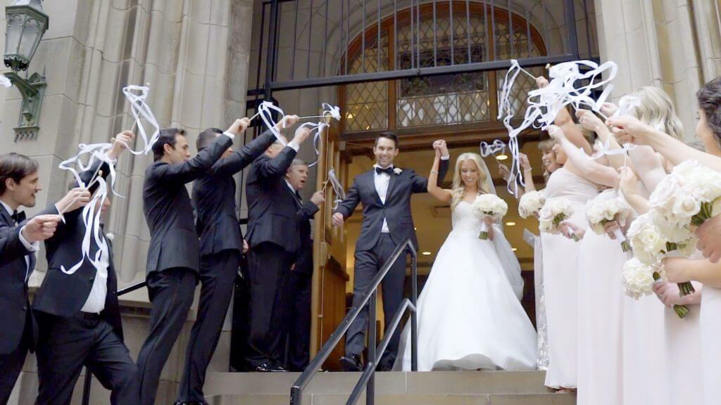 A group of people cheering bride and groom who going out of the church Chicago