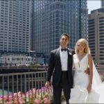 A bride and groom posing for a picture in front of a cityscape