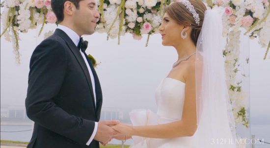 A bride and groom standing under a floral covered chute