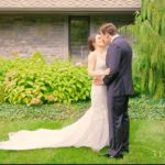 A bride and groom kissing in front of a house