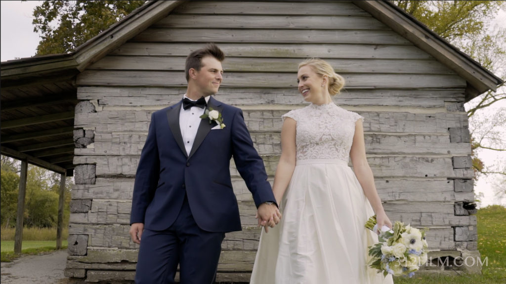 The bride and groom are holding hands in front of the cabin at the Glen View Club wedding.
