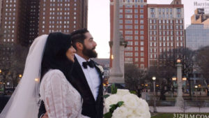The bride and groom are looking at the Chicago skyline, with the Blackstone Hotel in the background.