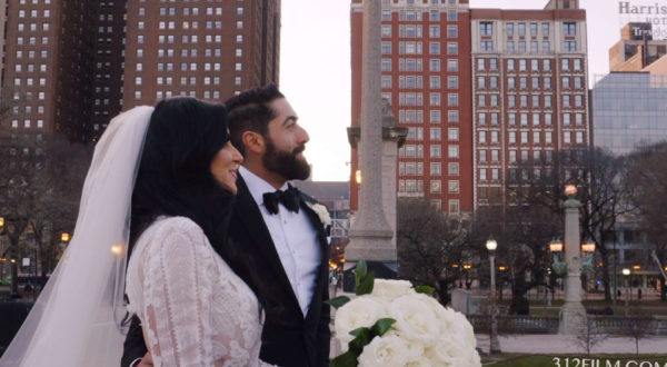 The bride and groom are looking at the Chicago skyline, with the Blackstone Hotel in the background.