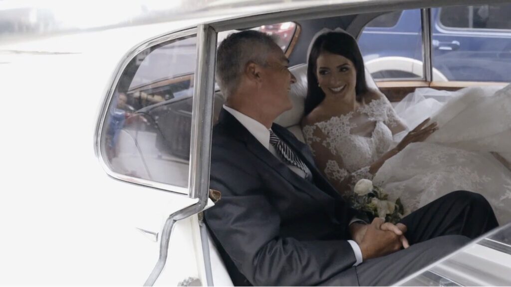 The bride and her father pose in front of an old Rolls-Royce in Chicago before the wedding.