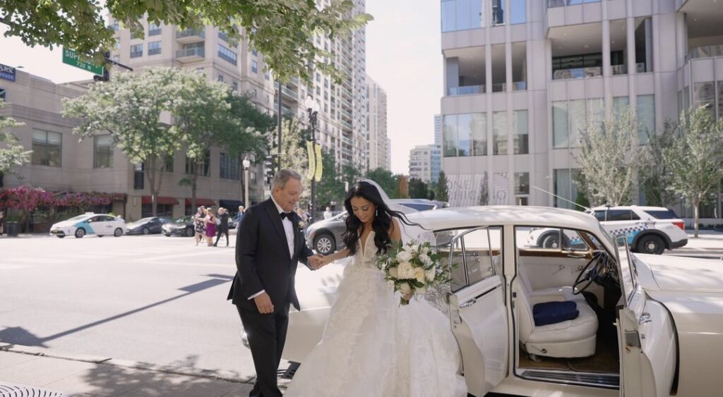 The bride is arriving at the church with her father in a classic car.