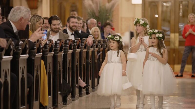 The flower girls walk down the aisle.