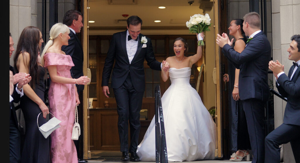 The bride and groom walk out of the church in Chicago on their wedding day, with hairstyles by Deco Amo.
