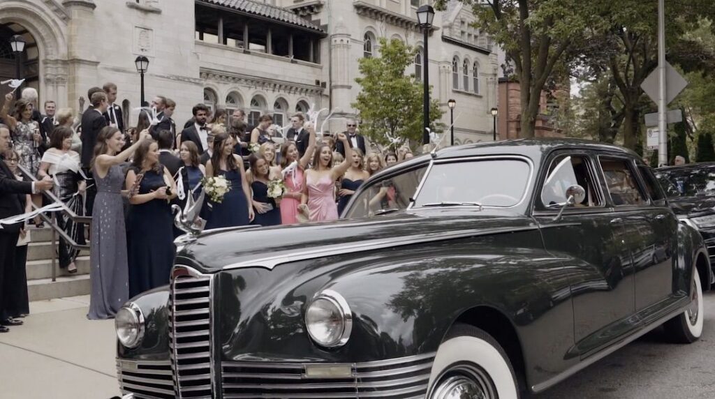 A vintage car waits outside Saint Clement's Church in Chicago, while guests cheer on the bride and groom.