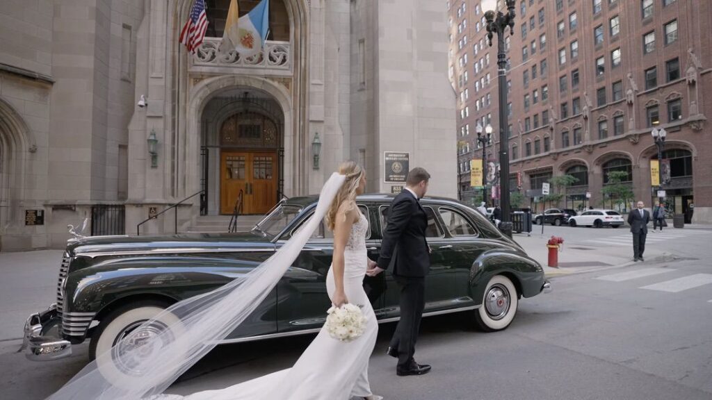 The bride and groom walk into the vintage car (Cloud 9 Limousine ) outside Saint James Chapel in Chicago.