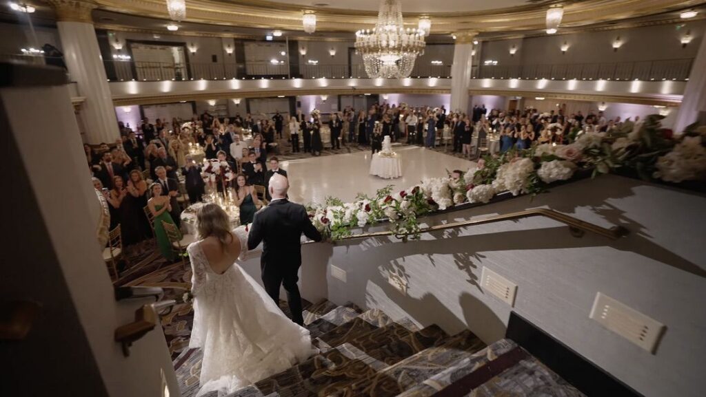 The bride and groom walk down the stairs into the reception at the Intercontinental Chicago for their wedding.