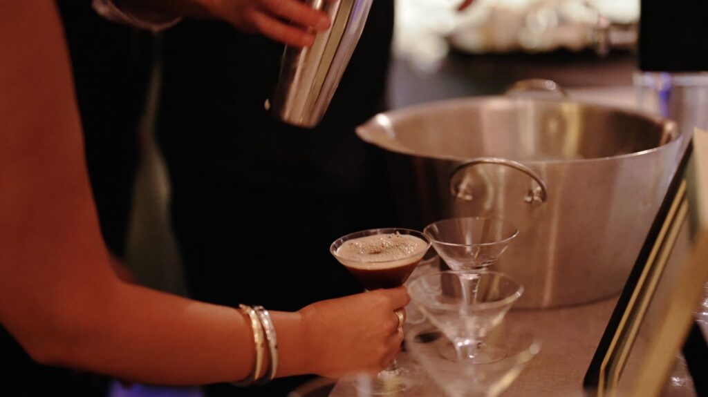 A bartender pours an espresso martini at the ice luge from Nadeau's Ice Sculptures at a Ritz-Carlton Chicago wedding.