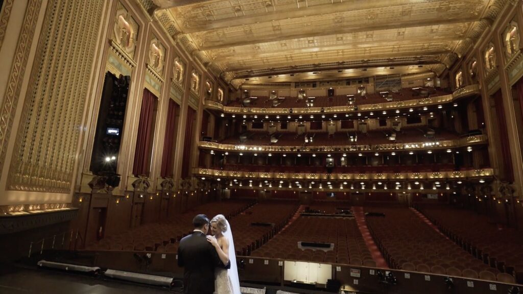 A couple are dancing their first dance on the stage of the Lyric Opera House, which has an incredible view.