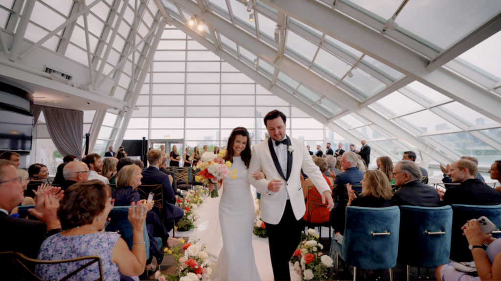 A couple walk down the aisle after their wedding ceremony at the Adler Planetarium.